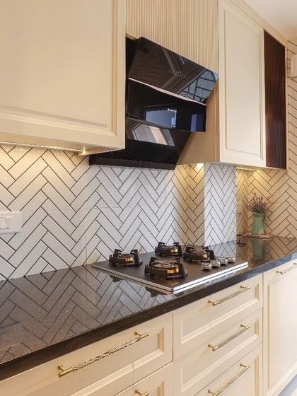 Another angle of the classic kitchen, showcasing the under-cabinet lighting that illuminates the black granite countertop and the elegant, fluted panel detail next to the chimney.
