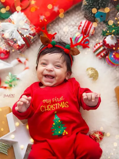 The happiest little reindeer. This baby's joyful laugh is the best Christmas gift. The festive red outfit and props create a perfect holiday card photo.
