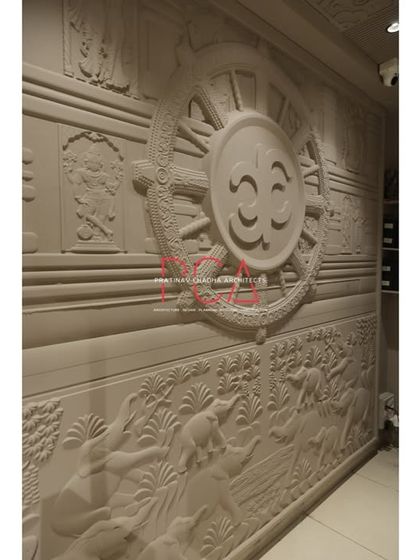 A detailed, angled shot of the large stone mural, revealing intricate carvings of figures and animals below the main motif.