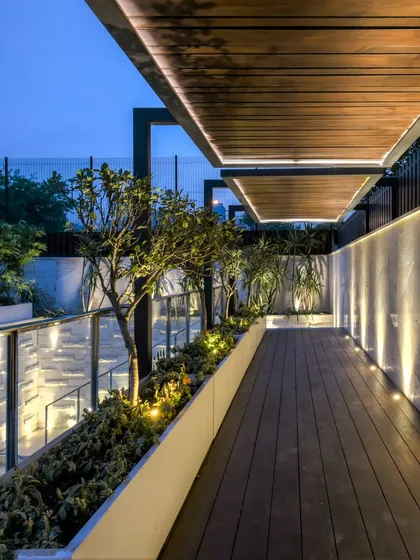 A long, narrow balcony transformed into a stylish walkway with a wooden deck, built-in planters, and a sleek pergola with integrated lighting. This shows our ability to make any outdoor space, regardless of size, both beautiful and functional.