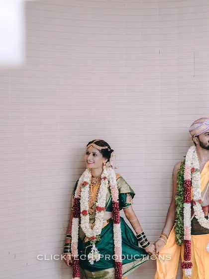 A quiet moment captured between the bride and groom, holding hands in their traditional wedding attire and garlands.