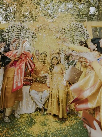 An explosion of yellow as friends and family shower the couple with marigold petals. This action shot perfectly encapsulates the vibrant energy of a Haldi celebration.