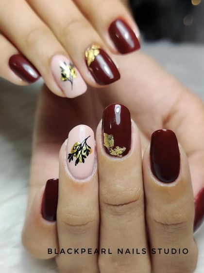 This design features a rich maroon polish with nude accent nails. I added hand-painted sticker-like art and gold foil to create a beautiful, artistic look on nails strengthened with Lexen gel.