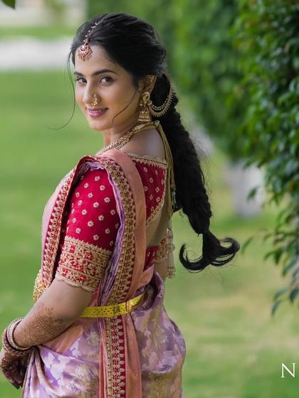 A smiling portrait of our bride Ranjitha, showcasing her custom red embroidered blouse and traditional South Indian bridal jewelry.