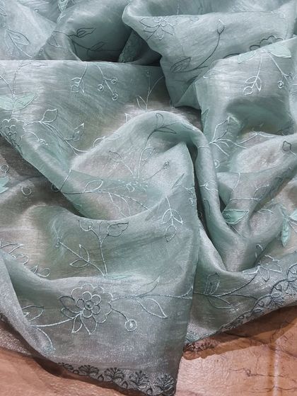 A pastel blue crush tissue saree with intricate tonal embroidery. This saree is the definition of understated elegance, perfect for those who love subtle details.