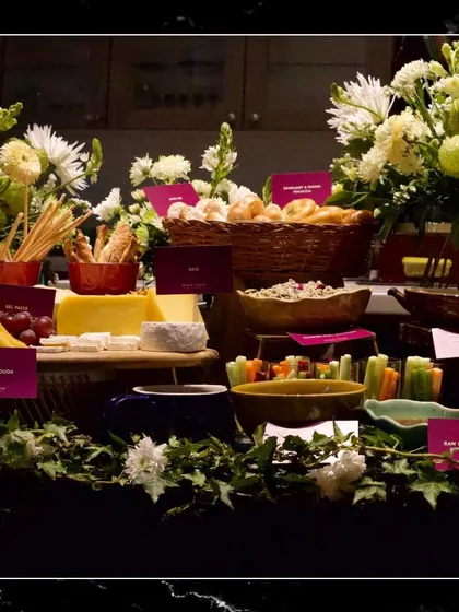 A beautifully composed grazing table where food and nature meet. The spread is adorned with fresh white flowers and ivy, creating a stunning visual that promises an equally impressive culinary experience.