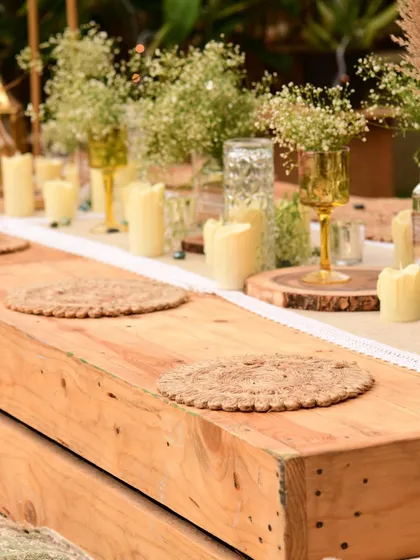 A close-up of the low wooden table, set with jute placemats and simple, elegant centerpieces that complement the natural theme.
