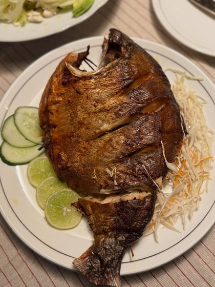 Our roasted whole fish served simply with shredded cabbage, cucumber, and lime. The focus is on the pure, smoky flavor of the perfectly cooked fish.