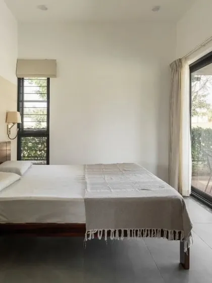 The master bedroom features large sliding glass doors that open directly onto a private sit-out and the garden. This seamless connection to the outdoors is a key feature of our residential designs.