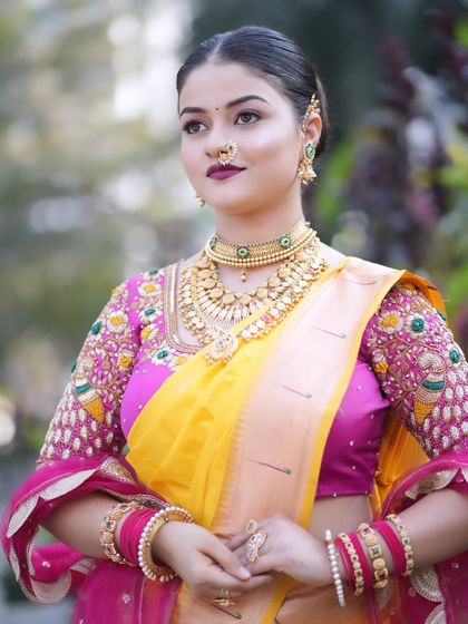 A full view of the bride's attire, showing the beautiful embroidery on her blouse and the elegant drape of her yellow silk saree.