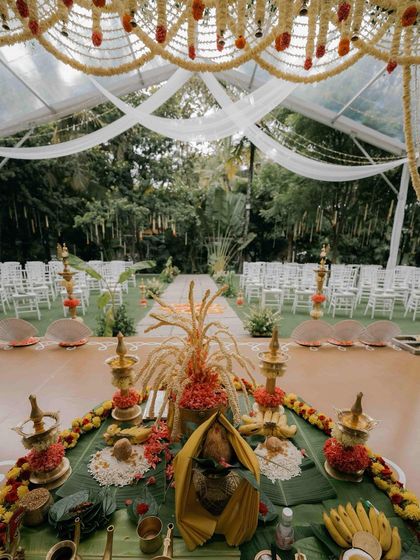 A view from the mandap looking out at the guest seating. The altar is meticulously prepared with traditional items like brass lamps, paddy stalks, and banana leaves for the ceremony.
