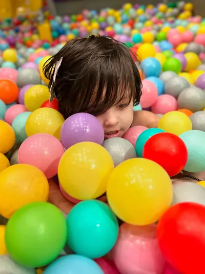 A close-up of the joy and wonder as a child plays in the ball pit.