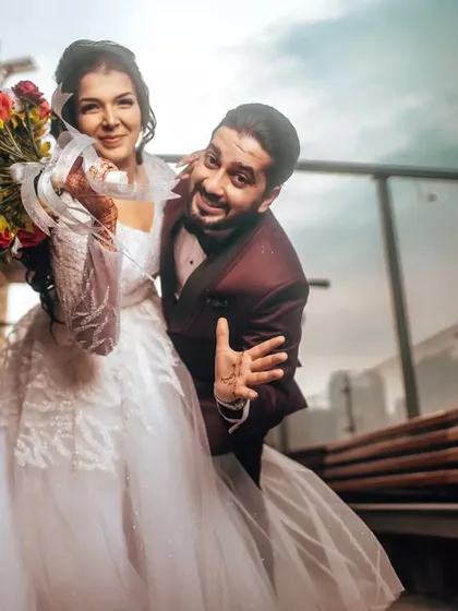 A fun, candid shot of a newly hitched couple. The groom's playful gesture and the bride's smile capture the excitement and lightheartedness of the moment perfectly.