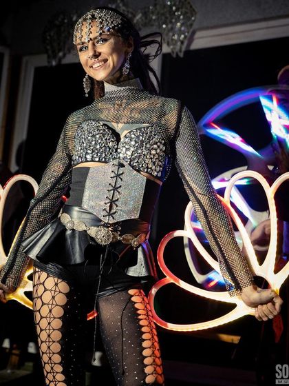 Our performer in a striking silver and black costume holds glowing LED fans. This edgy, glamorous look is perfect for nightclubs, fashion shows, and high-energy parties.