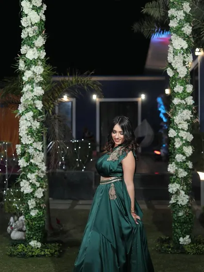 Another look at the beautiful green gown against a floral arch. The setting complements the outfit, creating a cohesive and visually appealing image.
