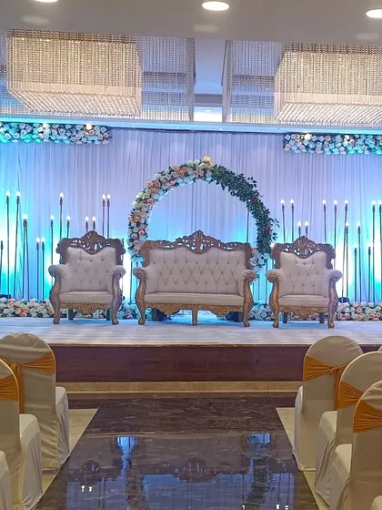 A classic reception stage at Ellora banquet hall with a circular floral arch and elegant candle stands. The white and green color palette offers a timeless and sophisticated ambiance.
