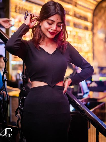 A guest posing on the stairs in a black cutout dress.