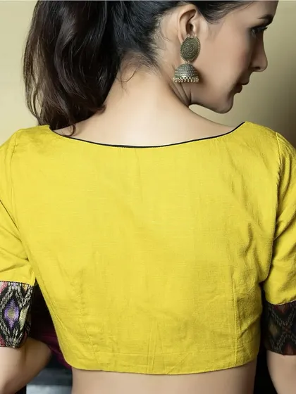 The back of our yellow cotton boat neck blouse. The simple, clean design is complemented by the unique print on the sleeve cuffs, adding a touch of character.