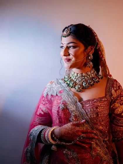 A beautifully lit portrait of the bride, highlighting her stunning green beaded necklace and makeup. The side profile captures her serene and thoughtful expression.