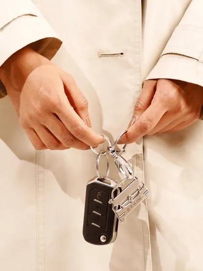 A detail shot focusing on a personalized keychain held by a model. This highlights the product's use in a subtle, sophisticated way, integrated into a stylish outfit.
