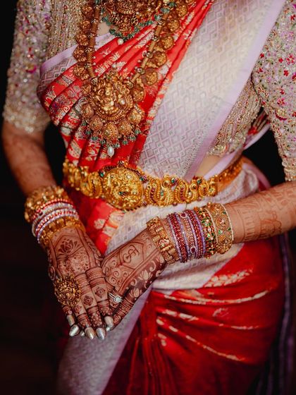A shot focusing on the bride's midsection, highlighting her gold waistband (vaddanam) and the rich mehendi on her hands.