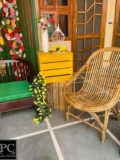 A detail shot of the side decor, featuring a cane chair and a yellow crate with a birdcage, adding to the bohemian charm of the Mehndi setup.