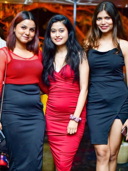 A stylish trio dressed in red and black, enjoying the vibrant atmosphere of our Wednesday party.