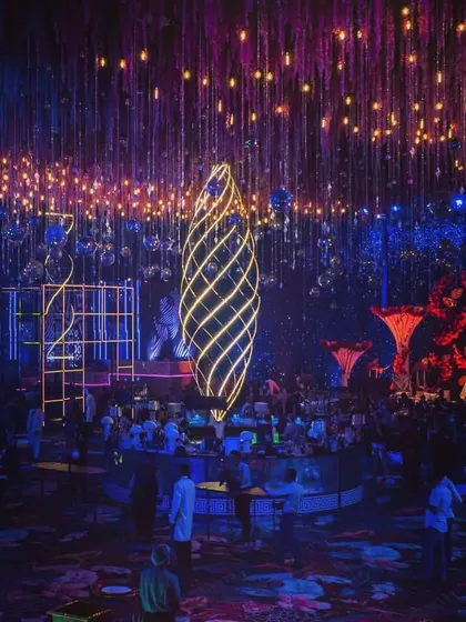 The centerpiece of a cosmic-themed party, featuring a large, illuminated spiral structure. The entire room is bathed in blue and purple light with hanging disco balls, creating a dynamic and electric atmosphere.