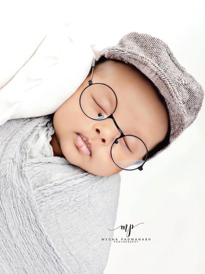 A different angle of the baby with the cap and glasses.
