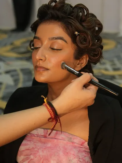 An artist applies blush to a model's cheeks, adding a healthy flush of color. Our training covers every step of creating a complete and balanced makeup look.
