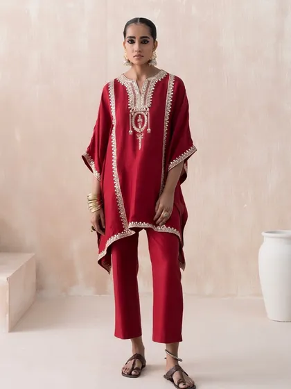 A clean, full-length lookbook shot for Saisha's "Firdaus" collection. The red embroidered kaftan is styled with simple, traditional footwear to keep the focus entirely on the garment's design and fit.