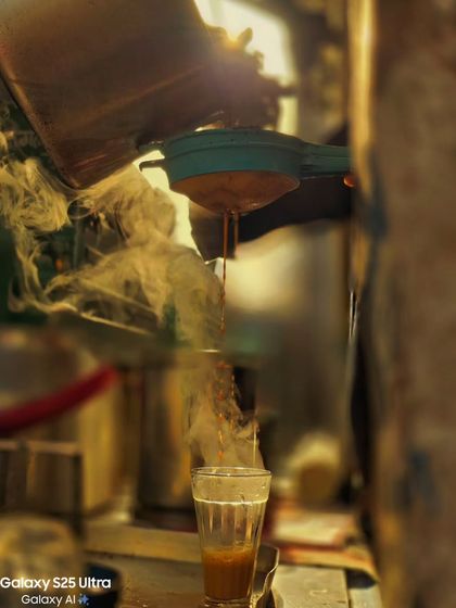 The steam rising from a fresh cup of chai creates a beautiful, atmospheric moment. A close up shot that captures the simple pleasures and sensory details of street life.