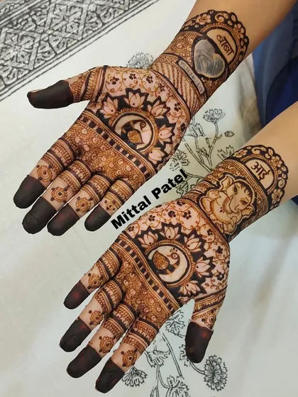 A spiritual baby shower design featuring Lord Ganesha on one arm and the word "Maa" on the other. The palms are decorated with peacock and lotus mandalas.