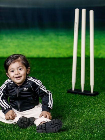 Even the littlest ones can join the cricket fun. This baby is all smiles, sitting on the "pitch" in his sporty Adidas tracksuit.