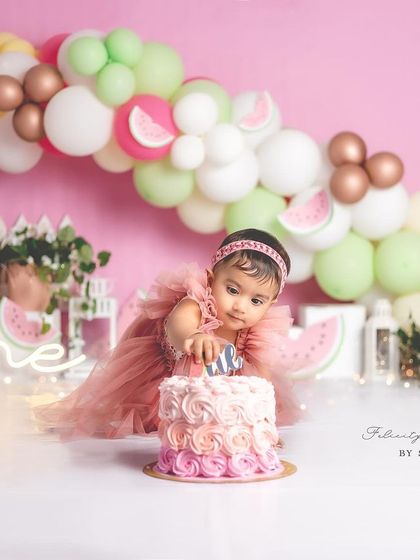A messy but happy one-year-old girl during her watermelon-themed cake smash.