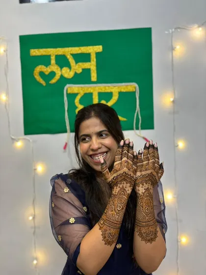 A happy, smiling bride showing off her elegant mehendi design.