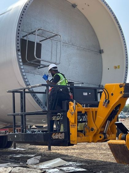 A technician performs quality checks on a wind turbine component. We meticulously source and inspect all materials to ensure minimal degradation and high output across the lifespan of our hybrid projects.