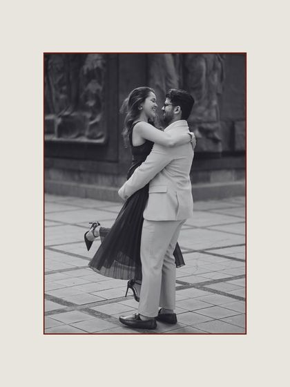 A joyful black and white photo of the groom lifting the bride in a playful embrace. This candid shot, set against the classic architecture of Georgia, is full of life and happiness.