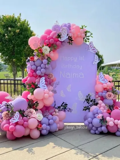 I can bring your party vision to life in any outdoor setting. This first birthday party features a beautiful pastel balloon arrangement in shades of pink, purple, and white with butterfly and flower accents, all set against a custom backdrop for a lovely garden party feel.