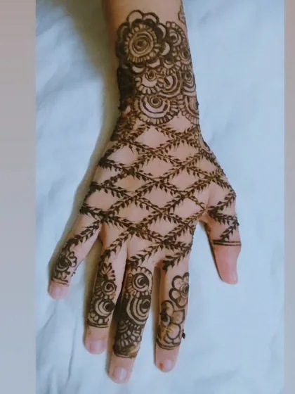A beautiful leafy jaal or net pattern on the back of the hand, combined with a floral cuff. This is a very elegant and popular party henna design.
