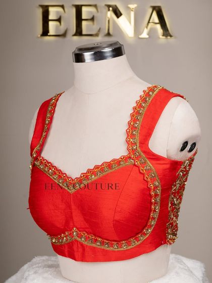 This sleeveless red blouse is perfect for a bold bridal statement. It features a deep V-neckline and is heavily embellished with intricate gold floral zardozi work, creating a rich and luxurious feel.