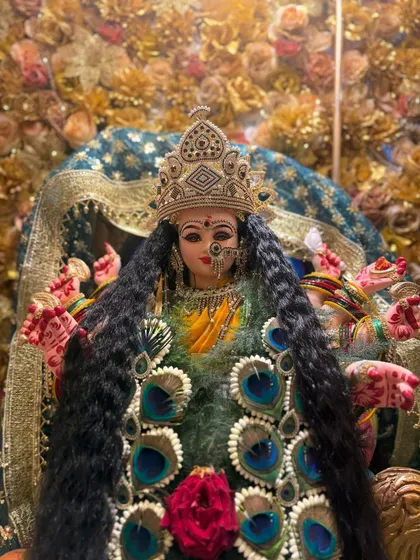 Another look at the Mayur Kanthi, showing how it beautifully adorns the deity for Navratri celebrations. The combination of green foliage, peacock feathers, and a central red rose creates a striking effect.