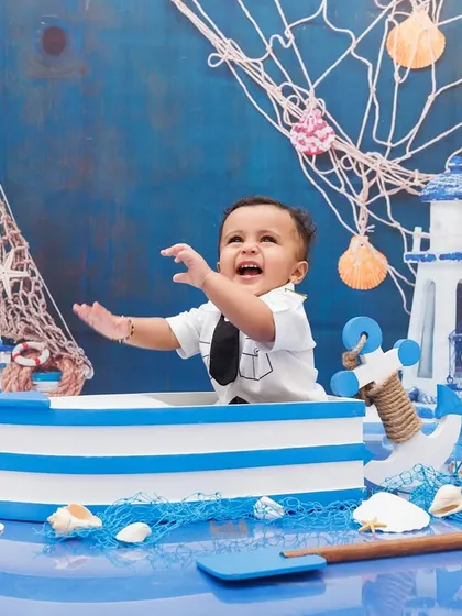 A candid moment of excitement from a one-year-old boy during his sailor-themed photoshoot.