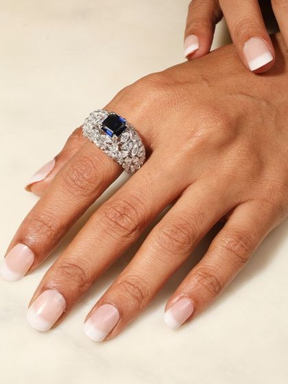 The Blue Sapphire Cocktail Ring worn on the hand, showing its bold presence and how the surrounding diamonds catch the light.