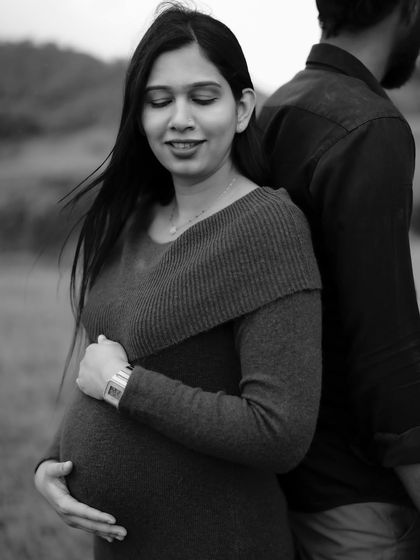 A serene black and white portrait. The mom-to-be leans against her partner, eyes closed, in a moment of complete peace and trust.