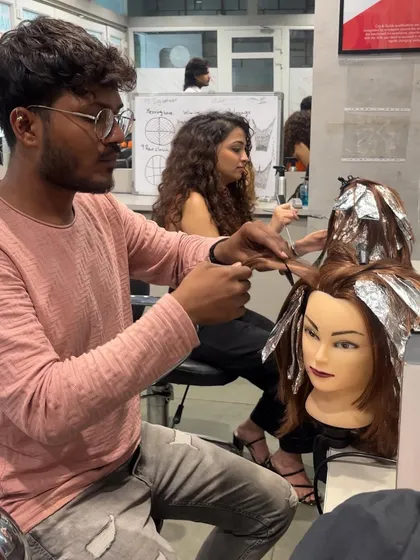 A student practices foiling techniques for highlights on a mannequin, an essential skill for any hair colorist.