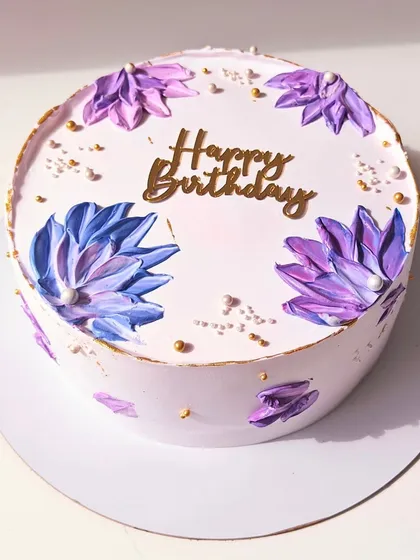 An aesthetic birthday cake with abstract, palette-knife painted flowers in shades of purple and blue. The gold accents add a touch of modern elegance.
