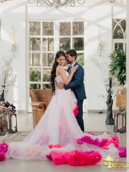 A full-length shot of the couple, capturing their loving embrace and the spectacular flow of the bride's gown.