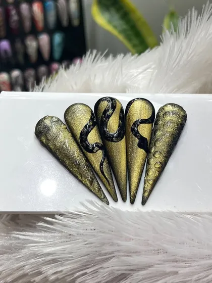 A luxurious take on the snake nail trend. This design features a black serpent over a textured, antique gold base for a truly opulent look.