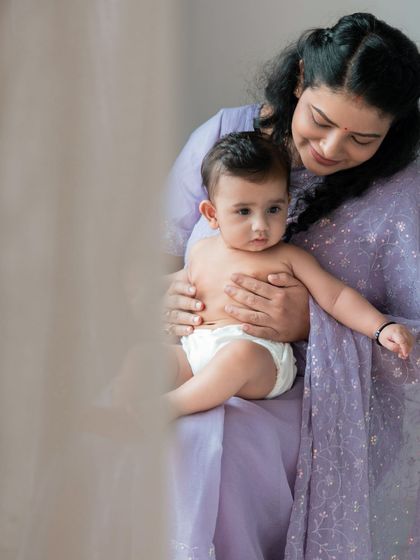 A mother's gentle embrace is a world of comfort for her baby. This soft, naturally lit portrait captures a quiet moment between a mother in a lovely lavender sari and her child.